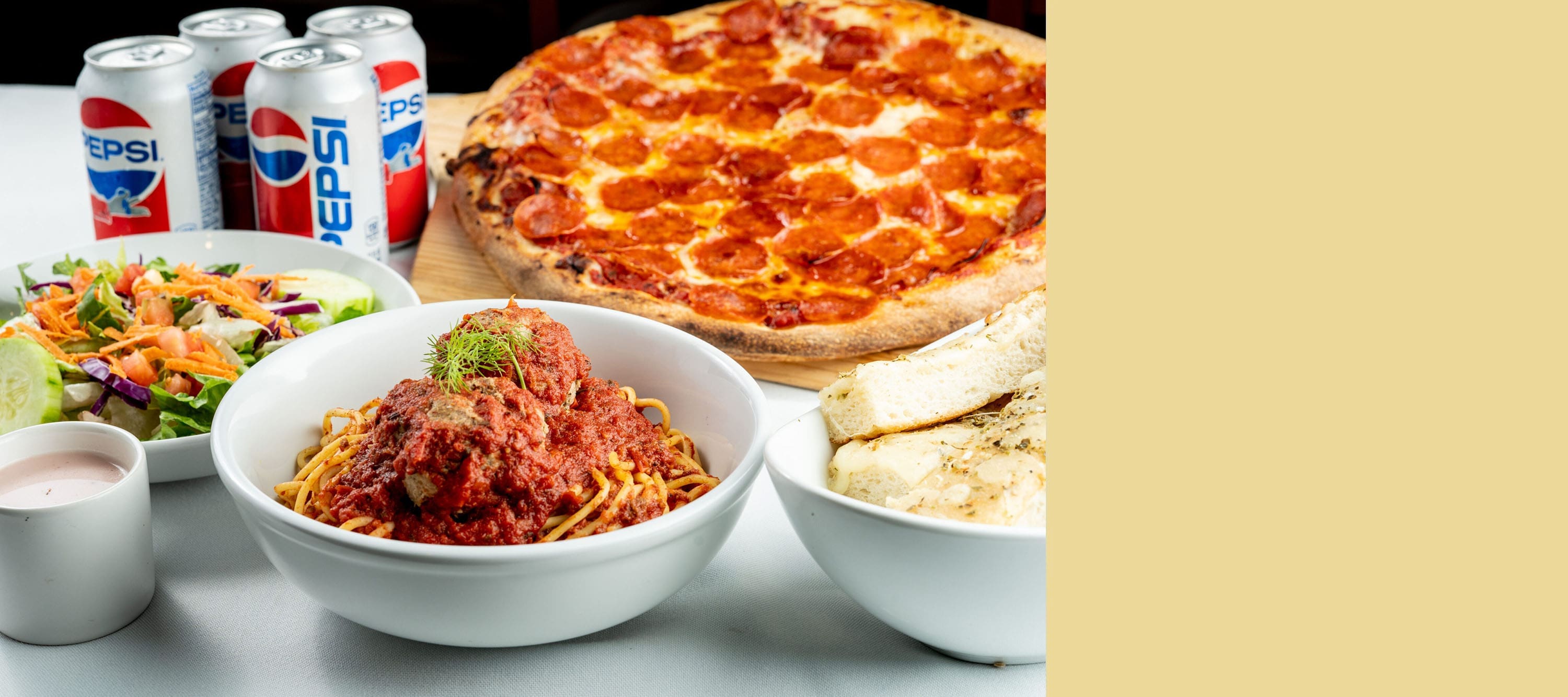 Spaghetti, pizza, salad, and drinks on table.